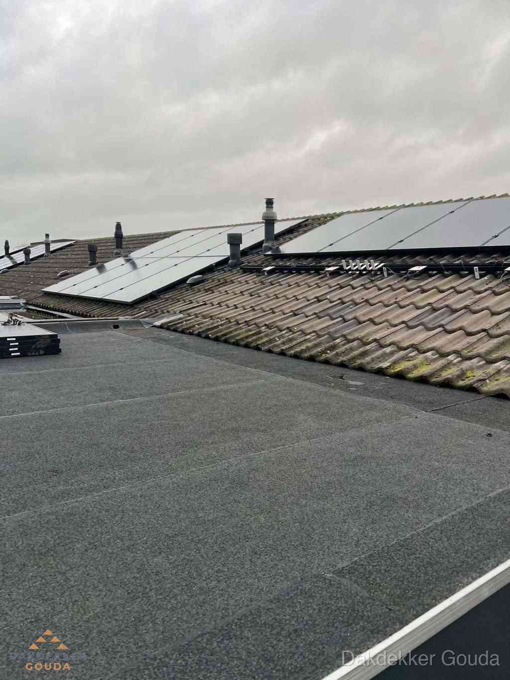 Plat dak inspectie met bitumen bedekking naast schuin pannendak in Gouda